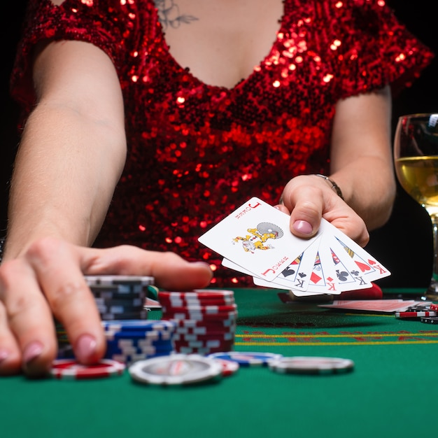 A girl in a red evening dress plays poker in a night casino