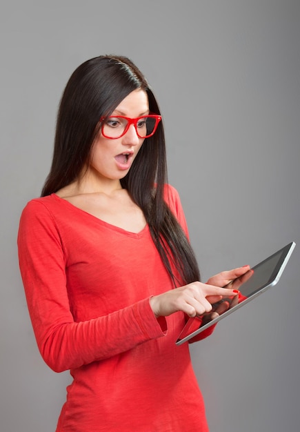Девушка в красных очках смотрит на экран планшетного ПК Pad