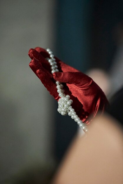 Girl in a red glove holding pearl beads