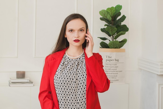 Girl in a red jacket talking on the phone in the office