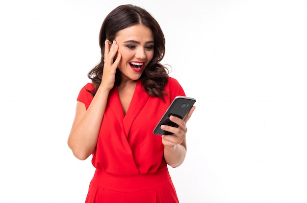 Девушка в красном комбинезоне удивленно смотрит на телефон