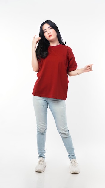 A girl in a red shirt and jeans stands in front of a white background.