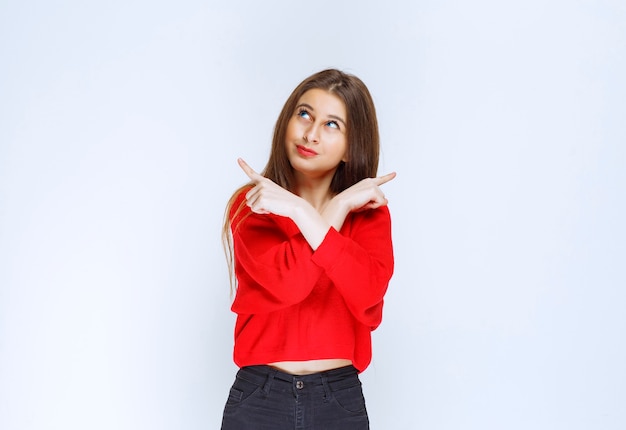 Girl in red shirt pointing upside. 