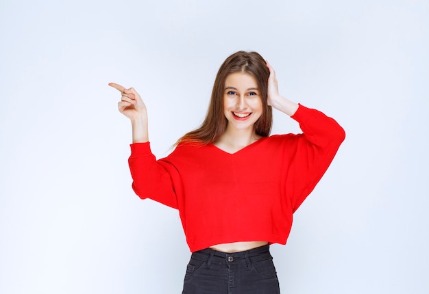 Girl in red shirt showing something on the left side. 