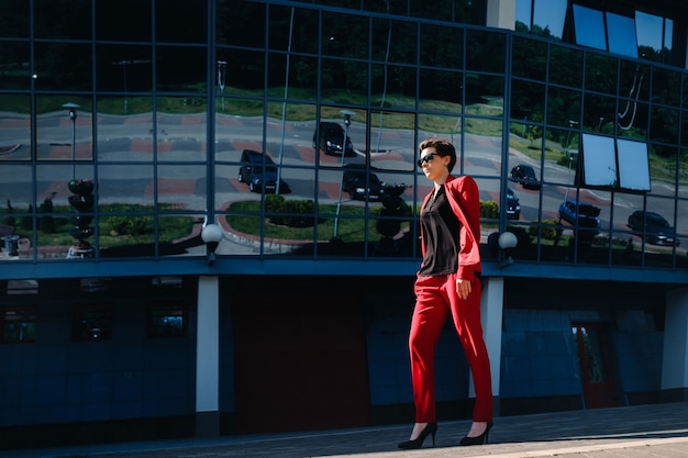 Foto una ragazza in abito rosso si erge sullo sfondo di un edificio moderno in città