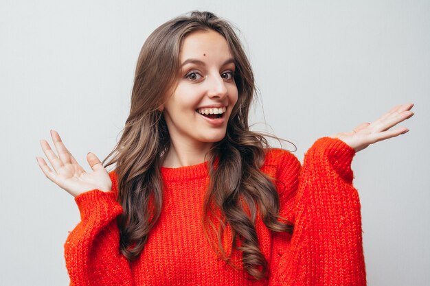 La ragazza in un maglione rosso sorride.