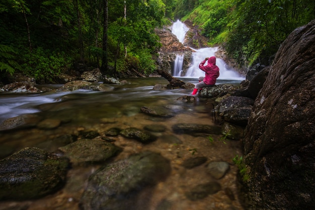 La ragazza in maglione rosso che fa un giro sulla cascata di pi-tu-gro, bella cascata nella provincia di tak, thailand.