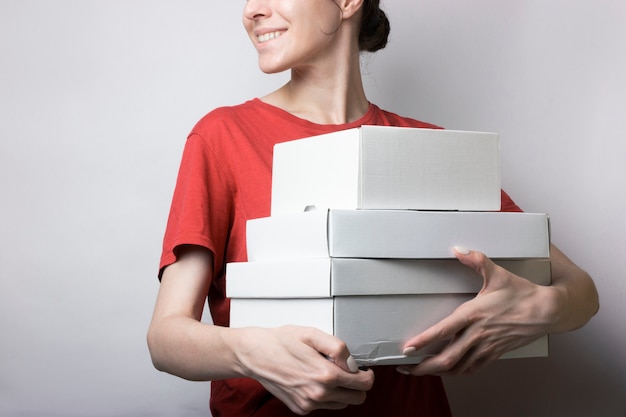 Girl in red t-shirt is holding a lot of cardboard boxes.