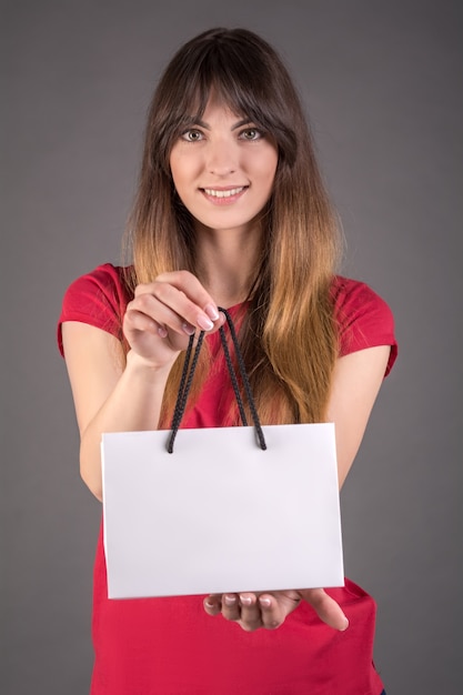 A girl in a red T-shirt with a white gift bag