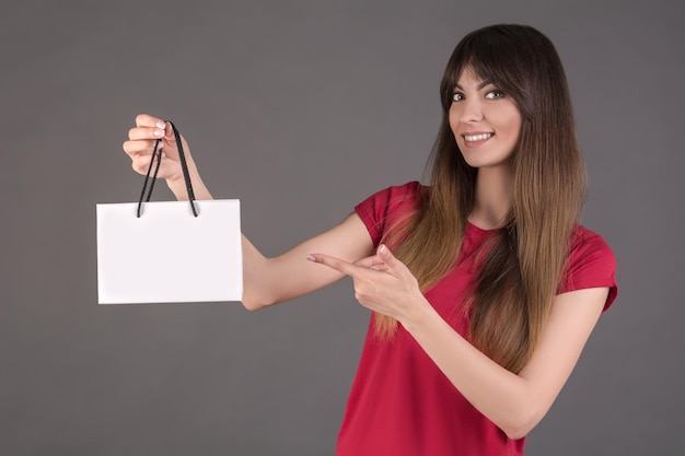 白いギフトバッグと赤いTシャツの女の子女性は製品を購入することを申し出ます