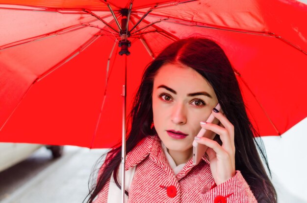 Girl under a red umbrella in the city