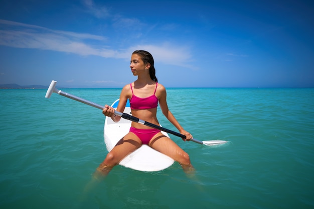 Foto ragazza rilassata seduta sulla tavola da surf paddle sup
