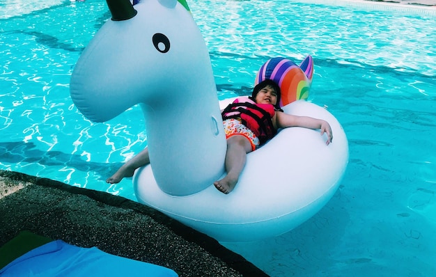 Girl relaxing on inflatable duck in swimming pool