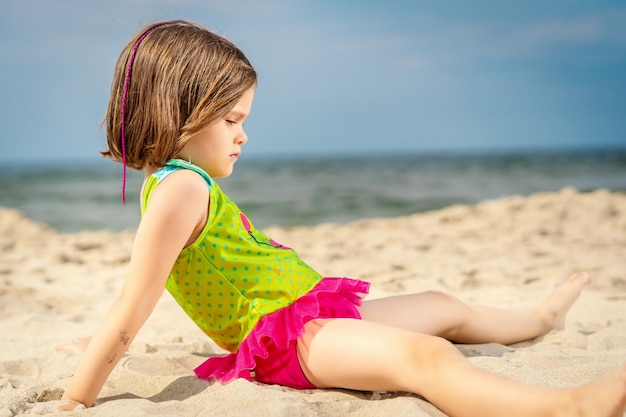 Photo girl relaxing on sand at beach against sky