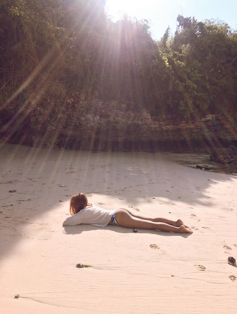 Foto ragazza che si rilassa sulla sabbia della spiaggia