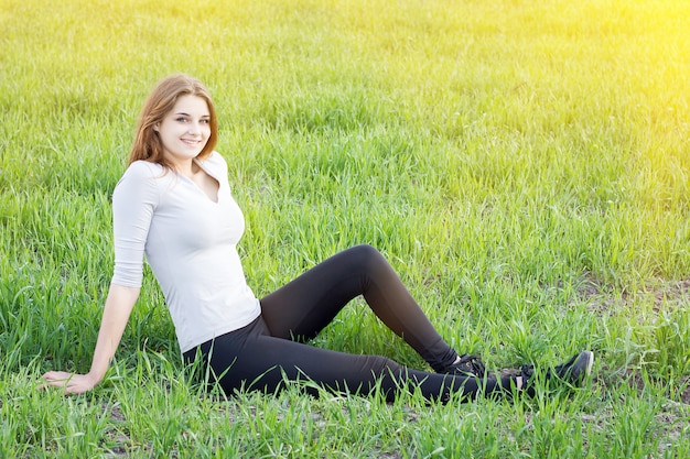 Girl resting on the green field. Camping