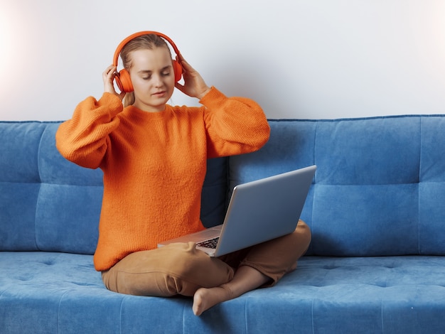 Girl resting at home in headphones at the computer