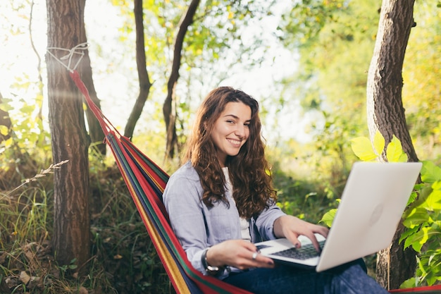 girl resting in the park with a laptop on a hammock