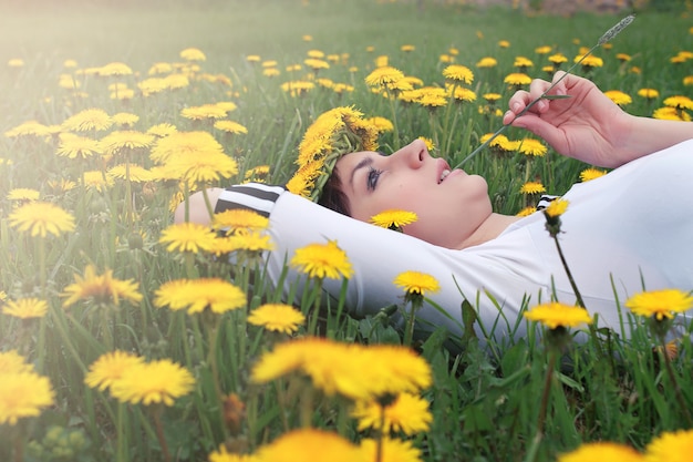 Girl resting on a sunny day in a meadow of yellow dandelions