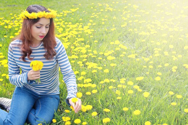 黄色いタンポポの牧草地で晴れた日に休んでいる女の子