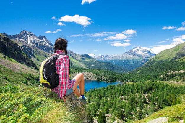 Girl resting during a trek in the mountains watching the view over a lake