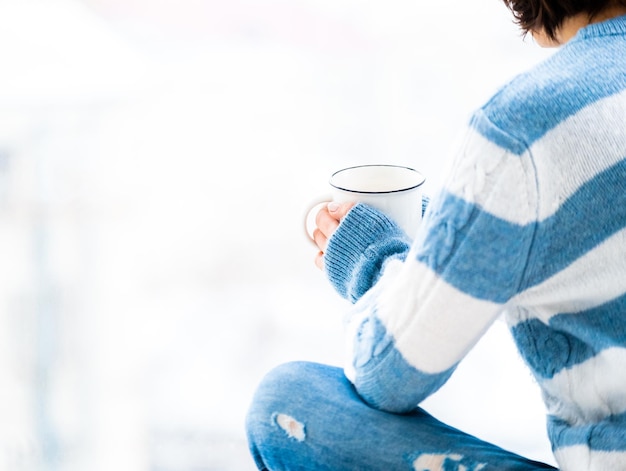 Girl resting with cup of tea sitting near window