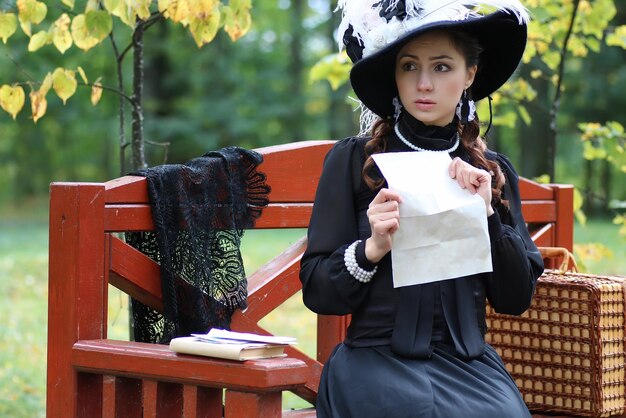 Girl in retro dress past century read letter on the bench