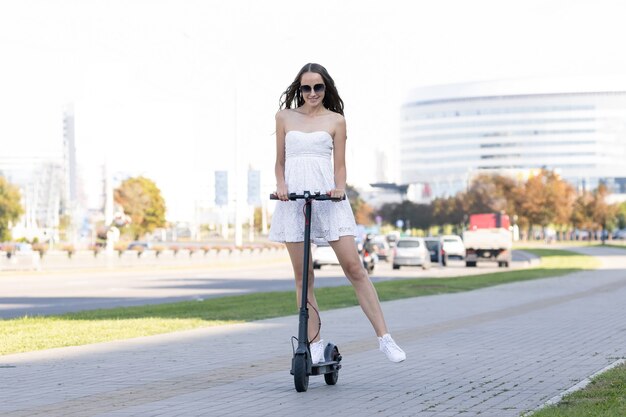 A girl rides around the city on an electric scooter in good weather