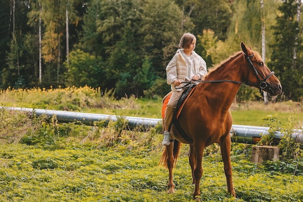 Una ragazza cavalca un cavallo in autunno nella foresta