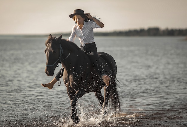 A girl rides a horse at a gallop on the beach