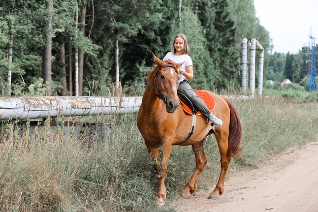 A girl rides a horse in the hot summer in the forest