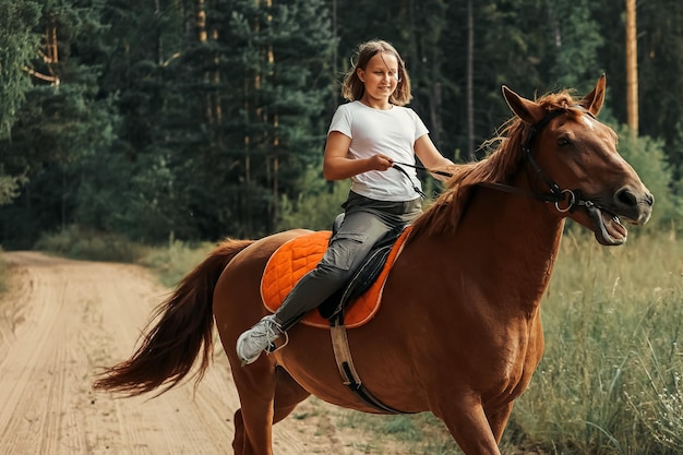 A girl rides a horse in the hot summer in the forest