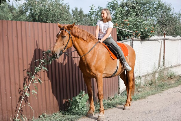 A girl rides a horse in the hot summer