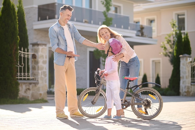 A girl riding a bike while her parents watching her