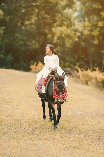 Photo girl riding horse on field