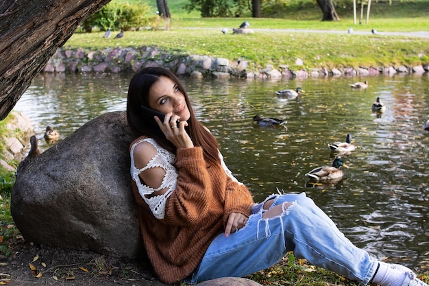 A girl on the riverbank is talking on the phone