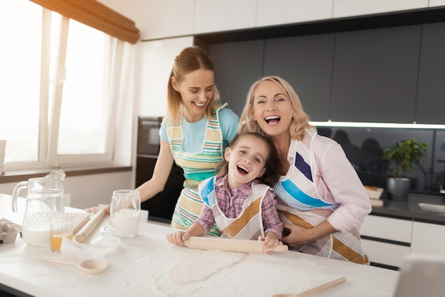 The girl rolls the dough with a rolling pin.