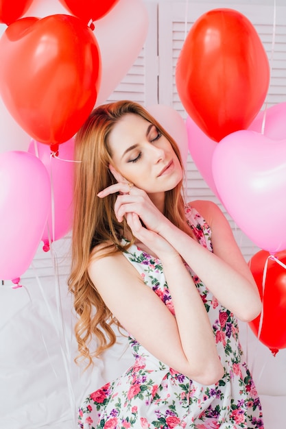 Girl in romantic dress with balloons in the shape of a heart