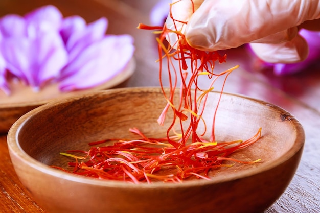 The girl in rubber gloves takes the saffron from a wooden plate Fresh saffron stamens