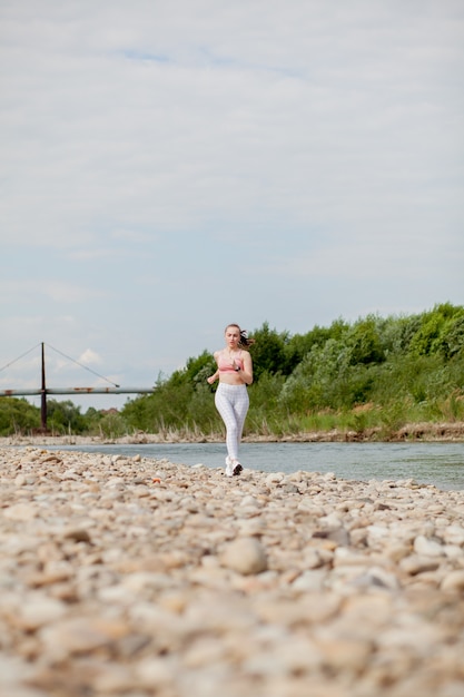 Corridore della ragazza che funziona dalla riva del fiume