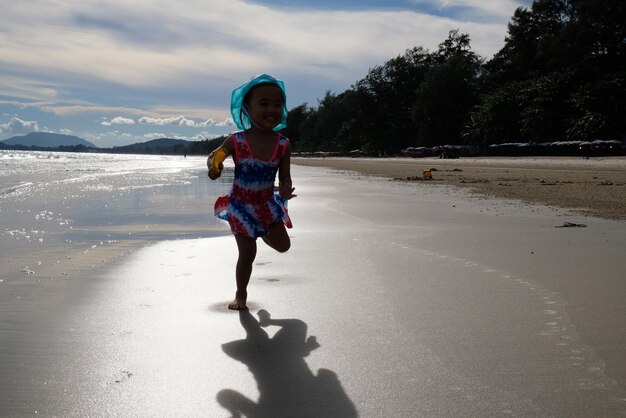 Foto ragazza che corre sulla spiaggia contro il cielo durante il tramonto