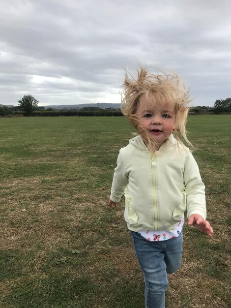 Foto ragazza che corre sul campo contro il cielo