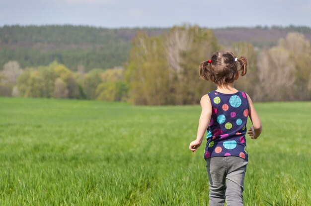 緑の野原で屋外を走っている少女