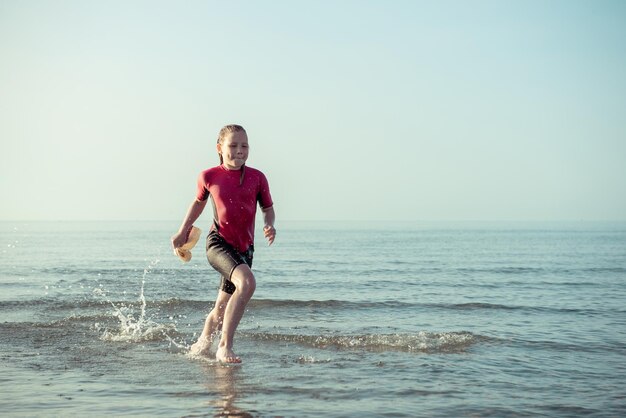 Girl running in sea against clear sky during sunny day