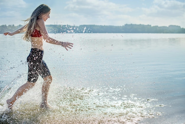 Girl running on the shore and splashing water