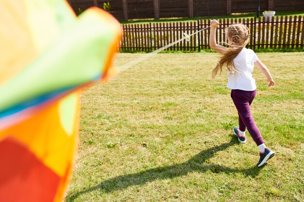 カラフルな凧で走っている少女