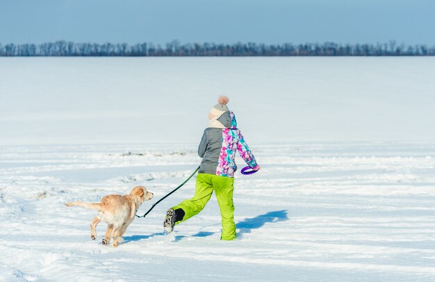 Ragazza che funziona con il cane in neve