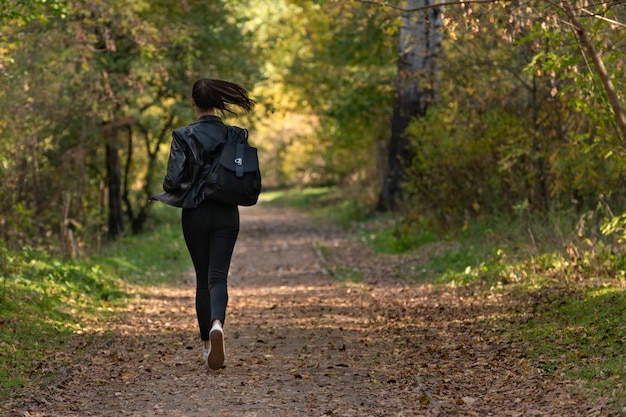 Girl runs along the park alley. woman runs away from someone in\
the park.