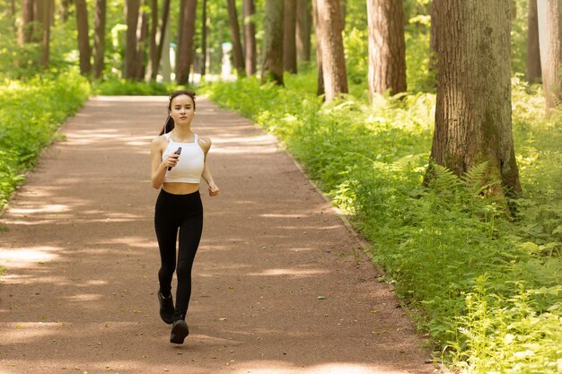 사진 소녀는 나무 사이 공원에서 헤드폰을 끼고 달린다