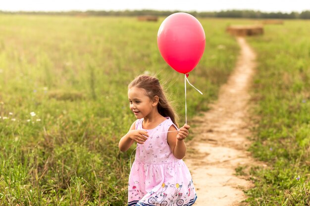 girl runs with red balloons in the summer in nature